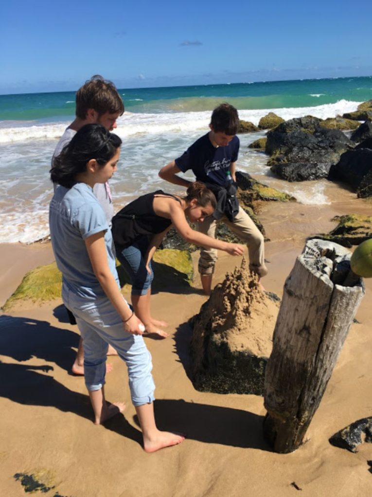 Julia Chin '21, Ethan Fielding '22, Brittney Sedgwick ' 21, and Ben Fruchtl '20 say their goodbyes to the ocean with a sand castle on the last morning of tour (Photo courtesy of Gettysburg College Choir)